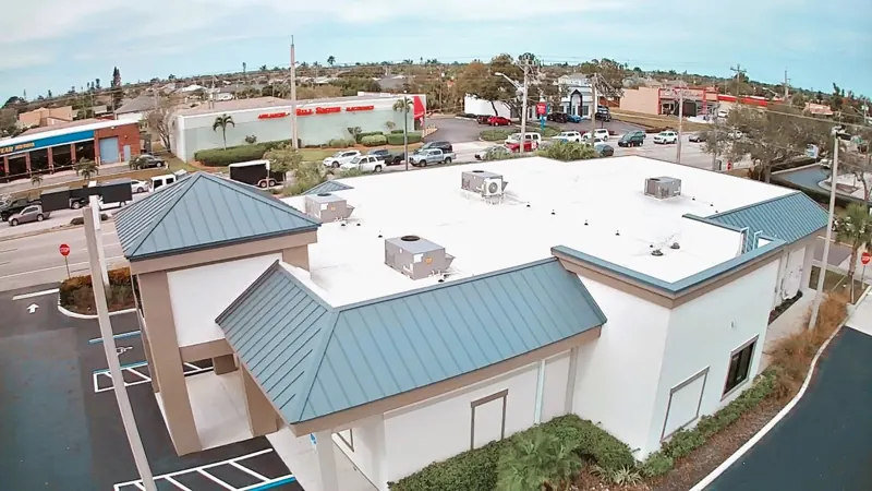 Aerial view of a flat white commercial roof with standing-seam metal accents, Big River Roofing